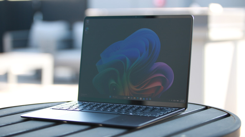 منظر من زاوية بعيدة قليلاً لجهاز Surface Laptop وهو جالس على طاولة في فناء على السطح.