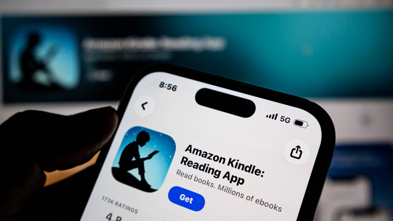 صورة ظلية لليد تحمل الهاتف مع تطبيق Amazon Kindle الجاهز في متجر pp الخاص بهواتفهم.